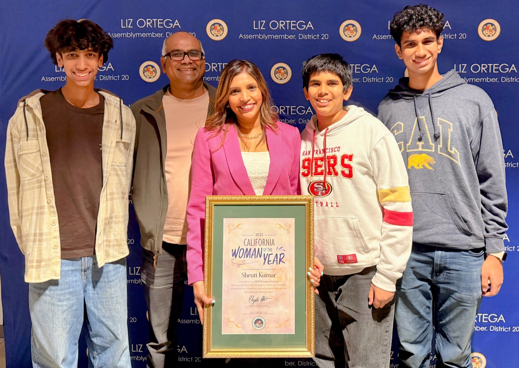 Shruti Kumar with family holding a Woman of the Year recognition